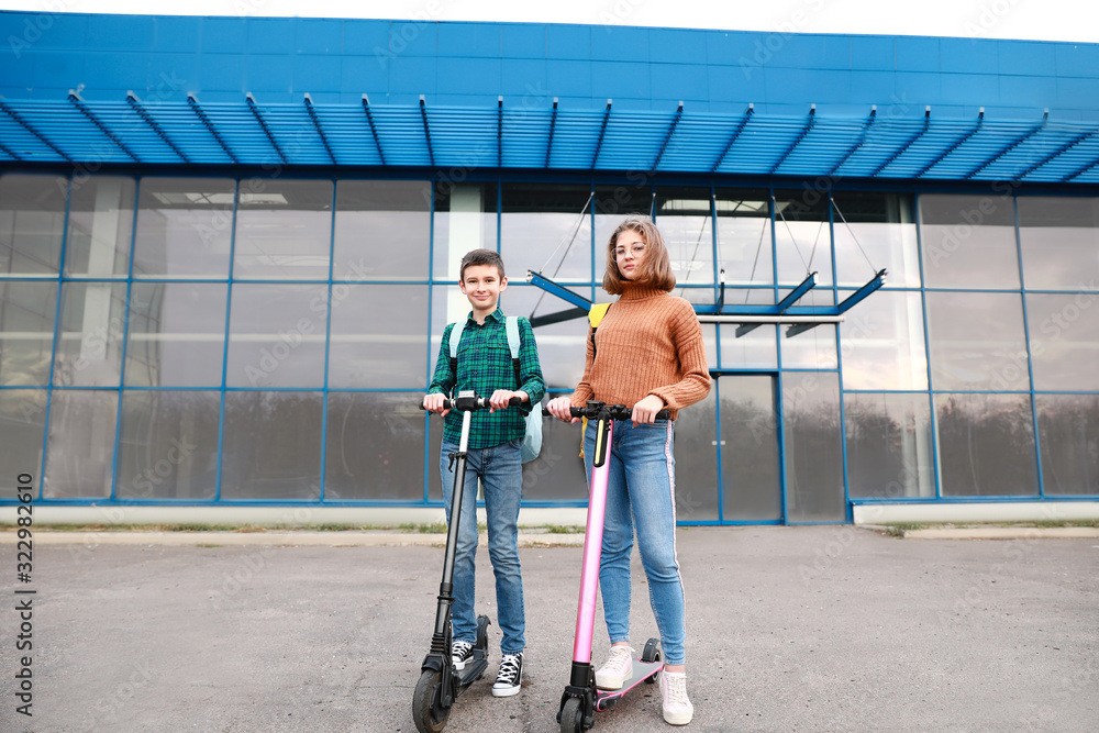 Active teenagers riding kick scooters outdoors