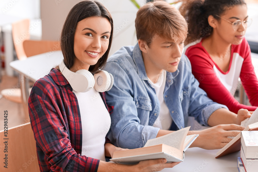 Young students reading books while preparing for exam in library