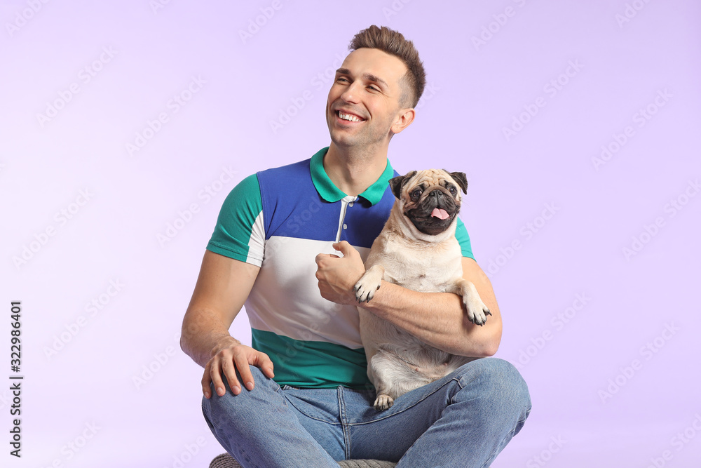 Handsome man with cute pug dog on color background