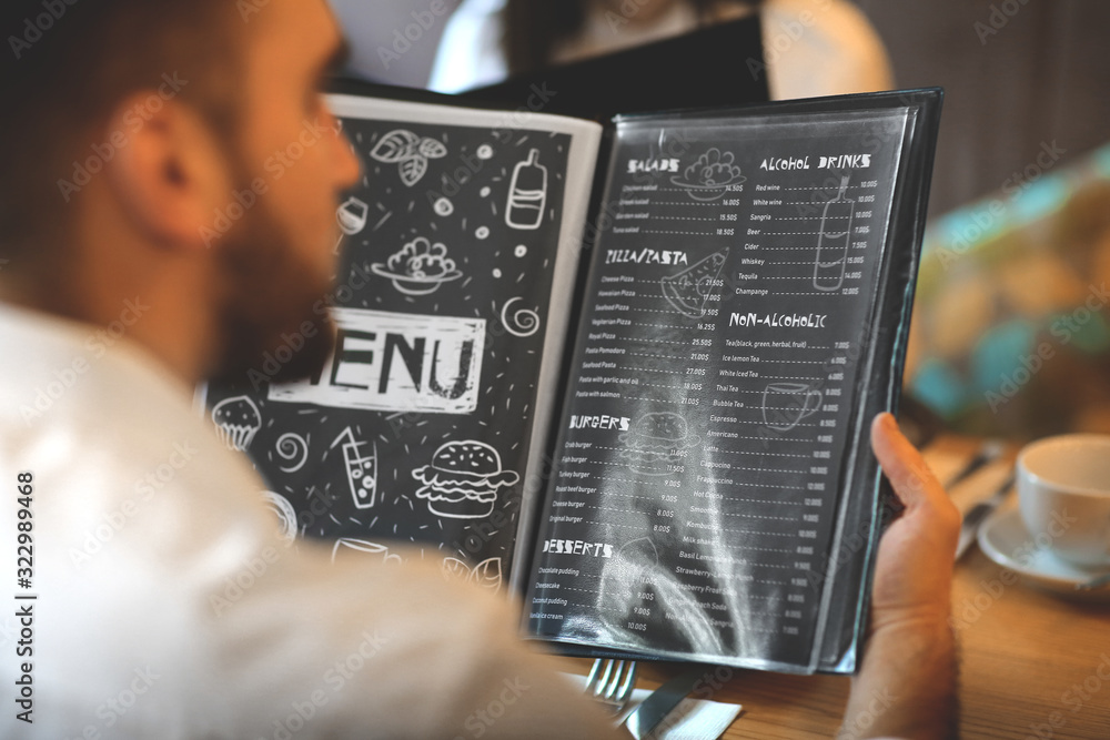 Young man with menu sitting in restaurant