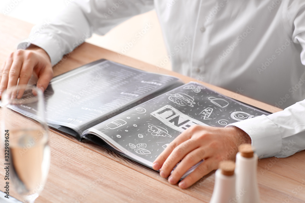 Young man with menu sitting in restaurant