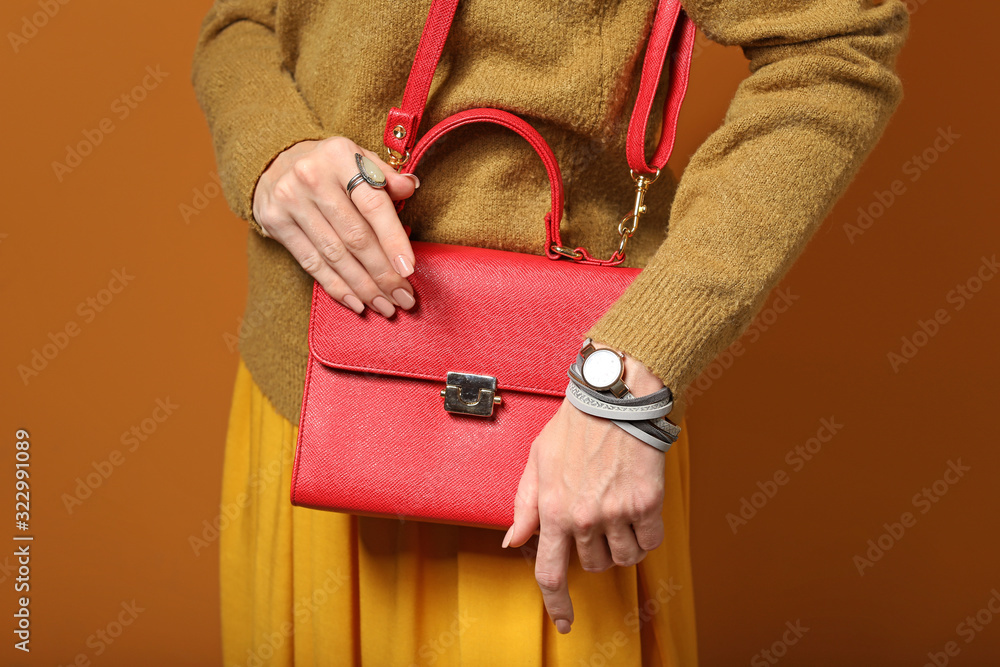 Young woman in warm sweater and with stylish bag on color background