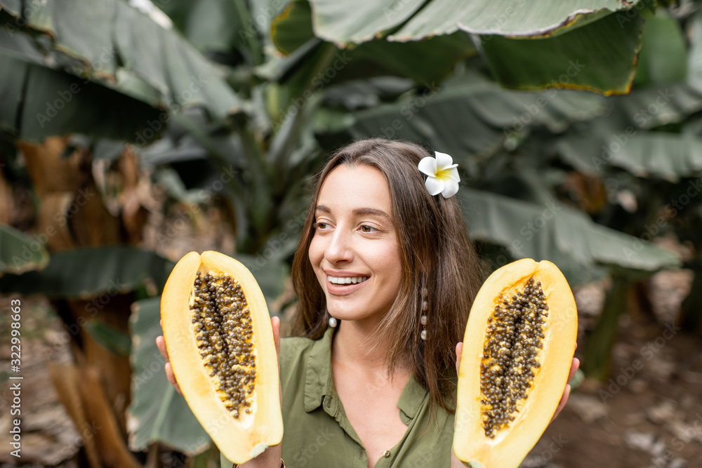 种植园里一个年轻女人拿着木瓜切片的肖像。素食主义的概念，治愈