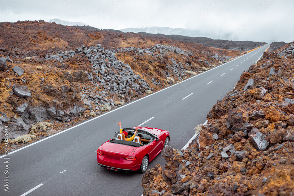 火山谷上美丽的笔直道路上的风景，一位女士开着一辆红色的cabrio