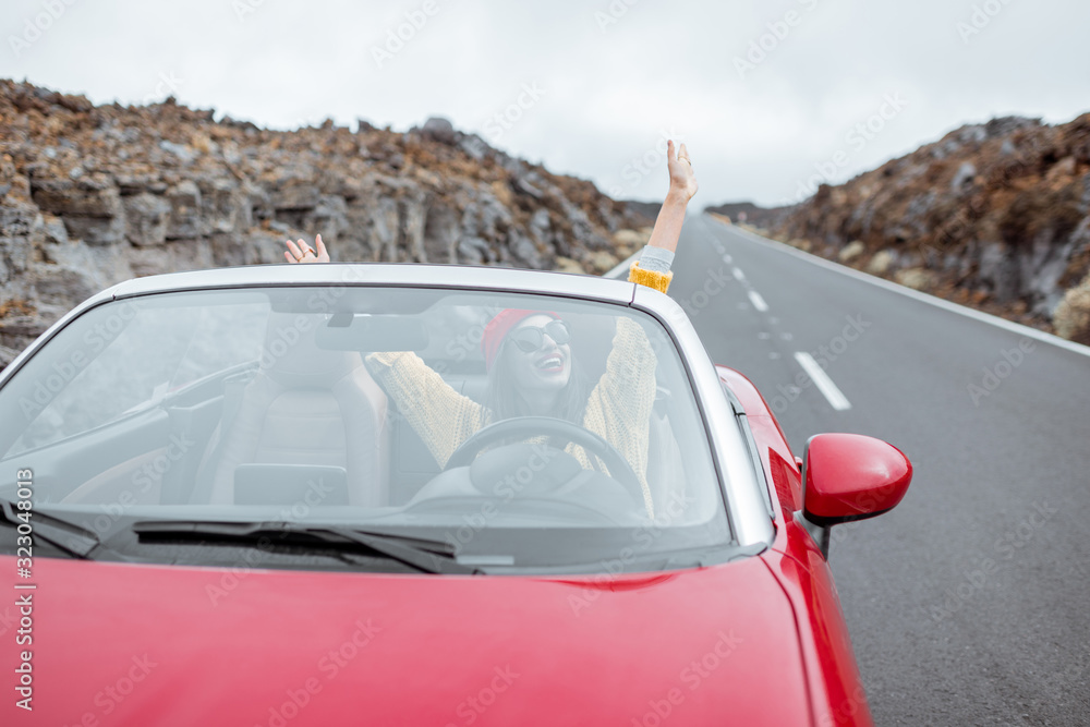 一位年轻女子乘坐敞篷车在火山口的方形道路上旅行的肖像