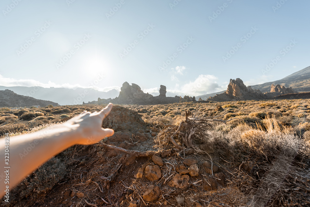 日落时，一名女子用手指着火山山，图像聚焦在背景上