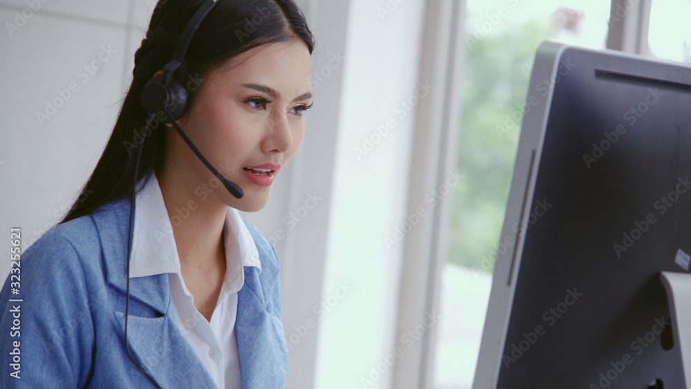 Customer support agent or call center with headset works on desktop computer while supporting the cu