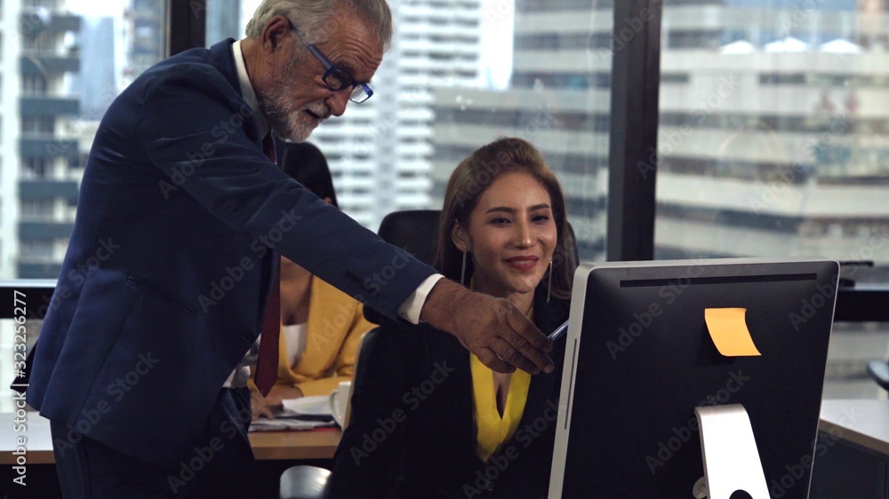 Senior manager gives advice to young woman worker in modern office. Leadership and training concept.