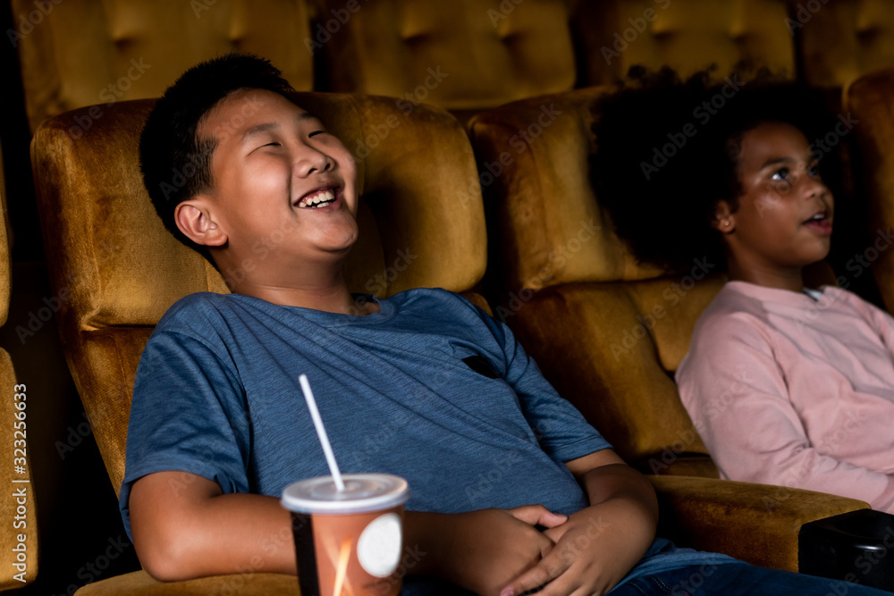 Three children having fun and enjoy watching movie in cinema