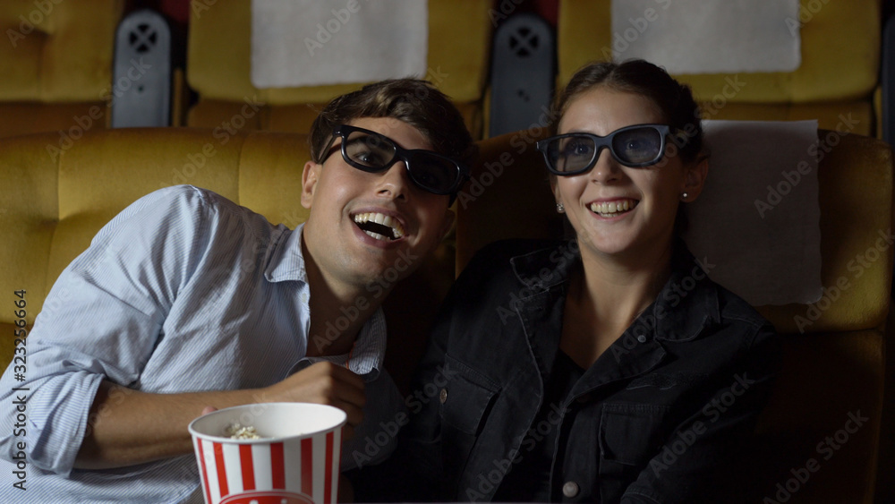 Man and woman in the cinema watching a movie with 3D glasses. with interest looking at the screen, e