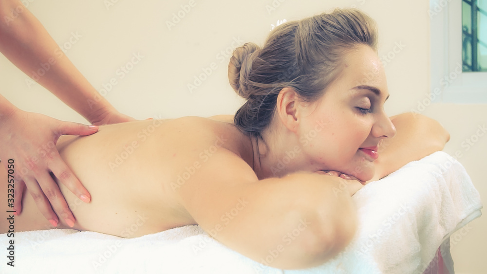 Relaxed woman getting back massage in luxury spa with professional massage therapist. Wellness, heal