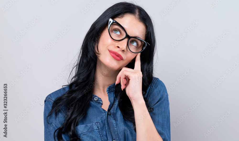 Young woman in a thoughtful pose on a gray background