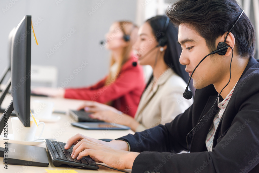 Attractive young man working in a call center with his colleagues