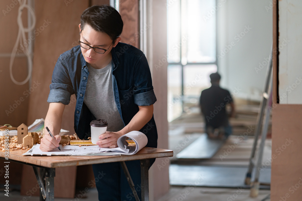 asian attractive glasses interior designer working at house site renovation construction progress wi