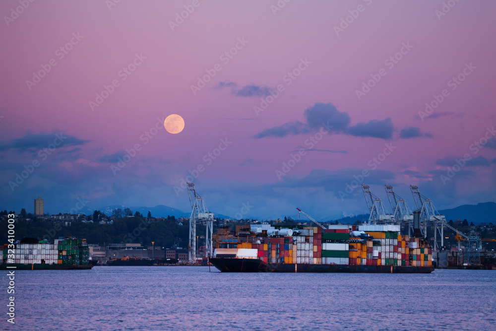 Cargo ship with containers in Seattle port at night over lune in the sky, Washington, USA