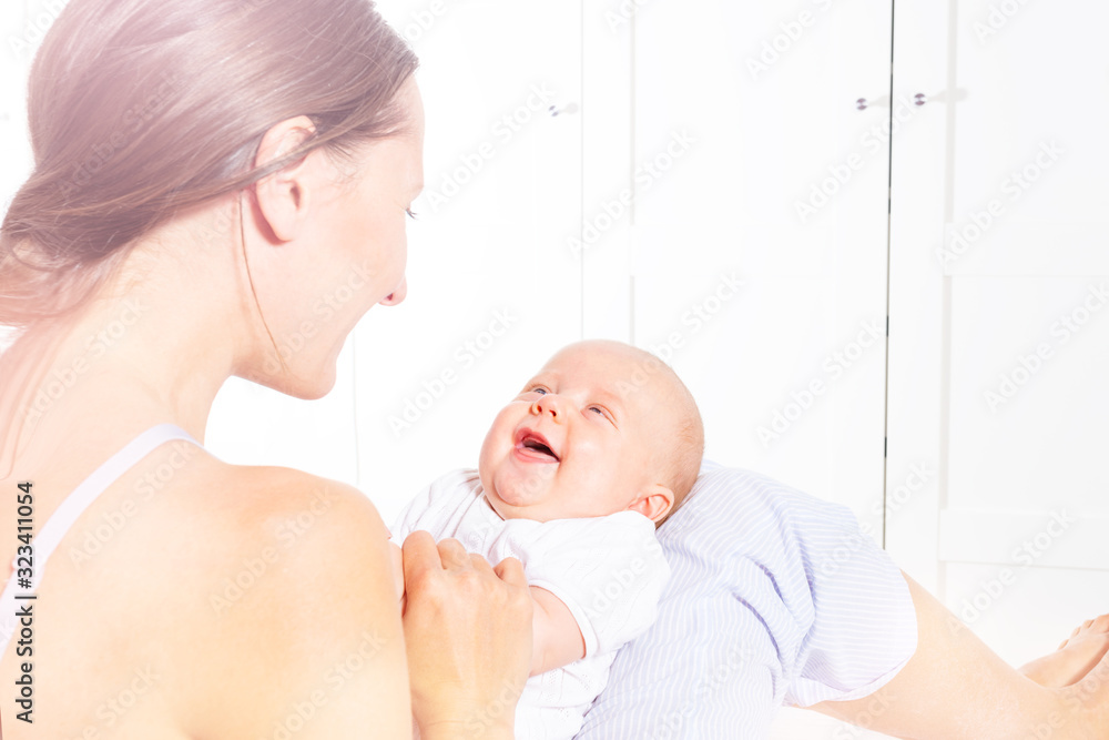 Happy mother play and talk to little newborn infant baby boy who laugh