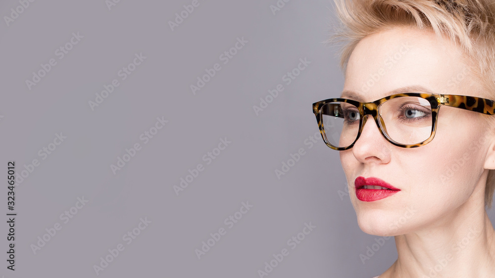 portrait of a young woman, blonde, glasses over grey background