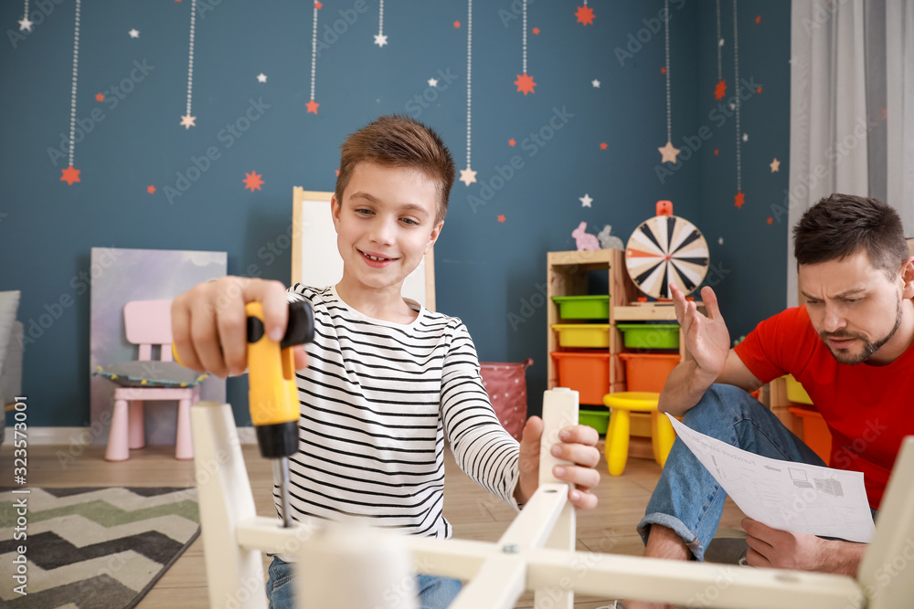 Father and his little son assembling furniture at home