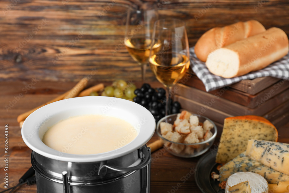 Cheese fondue with snacks on wooden background