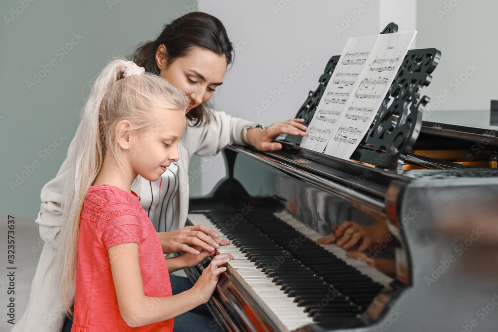 Private music teacher giving piano lessons to little girl