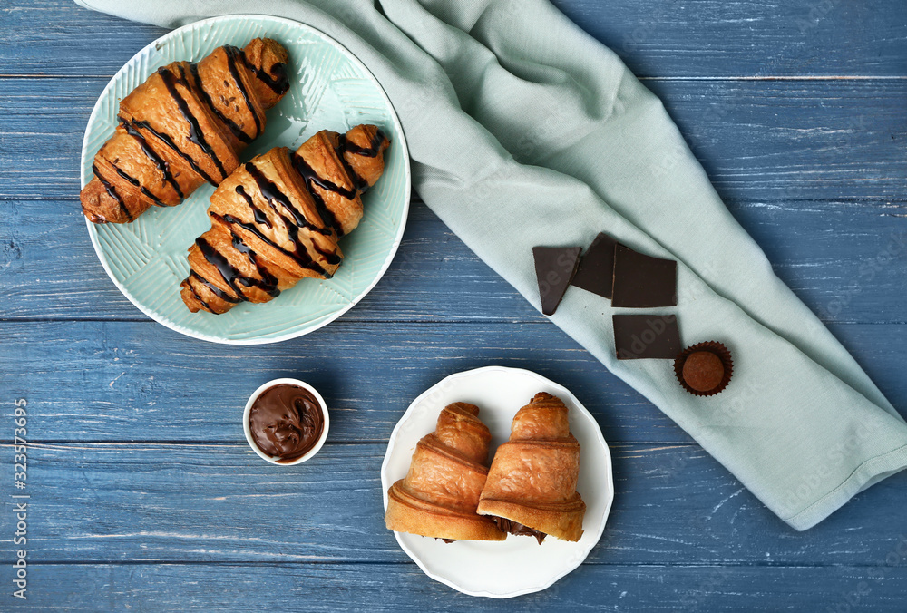 Plates with tasty sweet croissants and chocolate on table