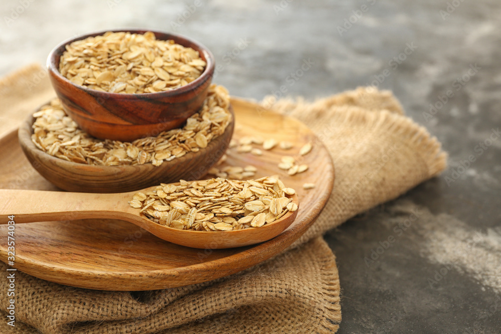 Bowls and spoon with raw oatmeal on table