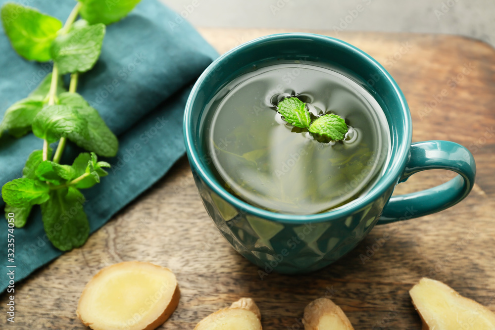 Cup of hot tea with ginger and mint on table