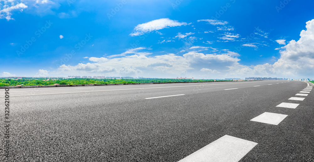 阳光明媚的上海，空旷的柏油公路和城市郊区的天际线。