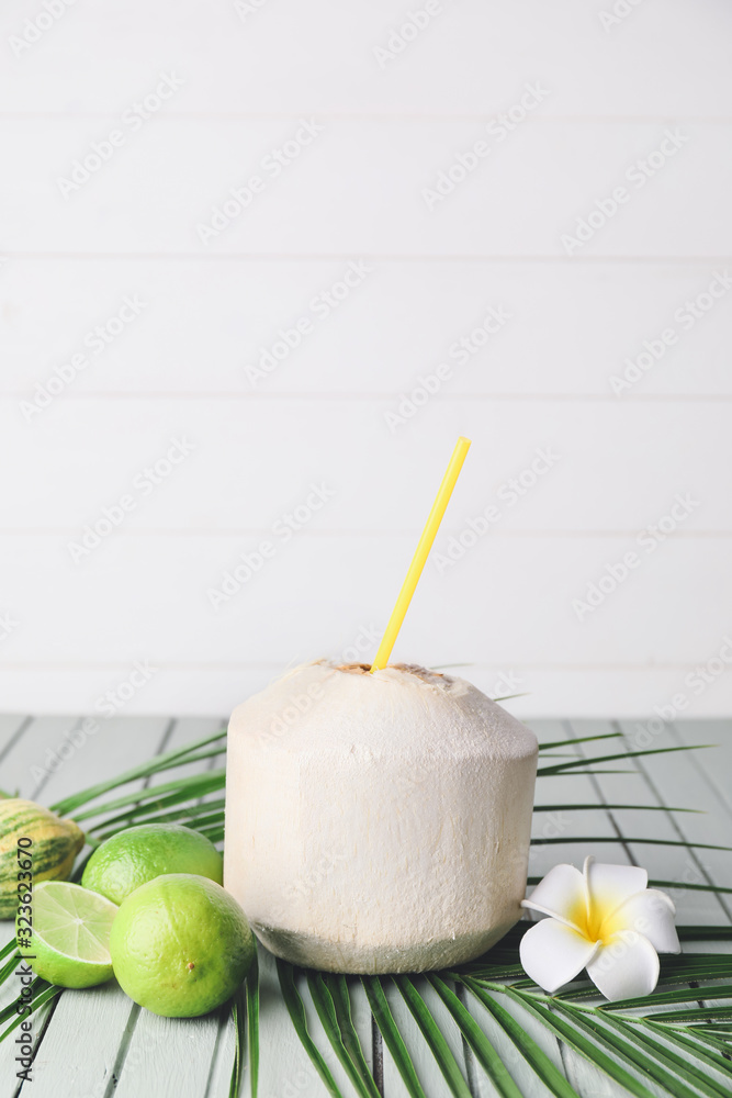 Young coconut with straw and limes on table