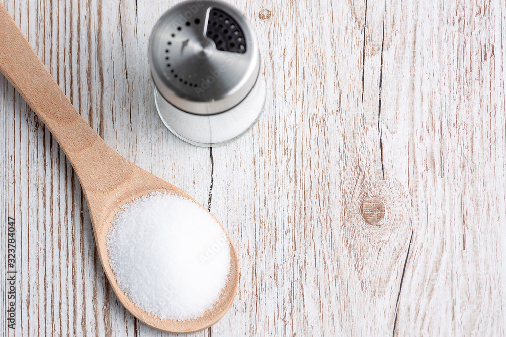 White sea salt for cooking food in Small glass bottles, wooden spoons, and trays on Old wooden table