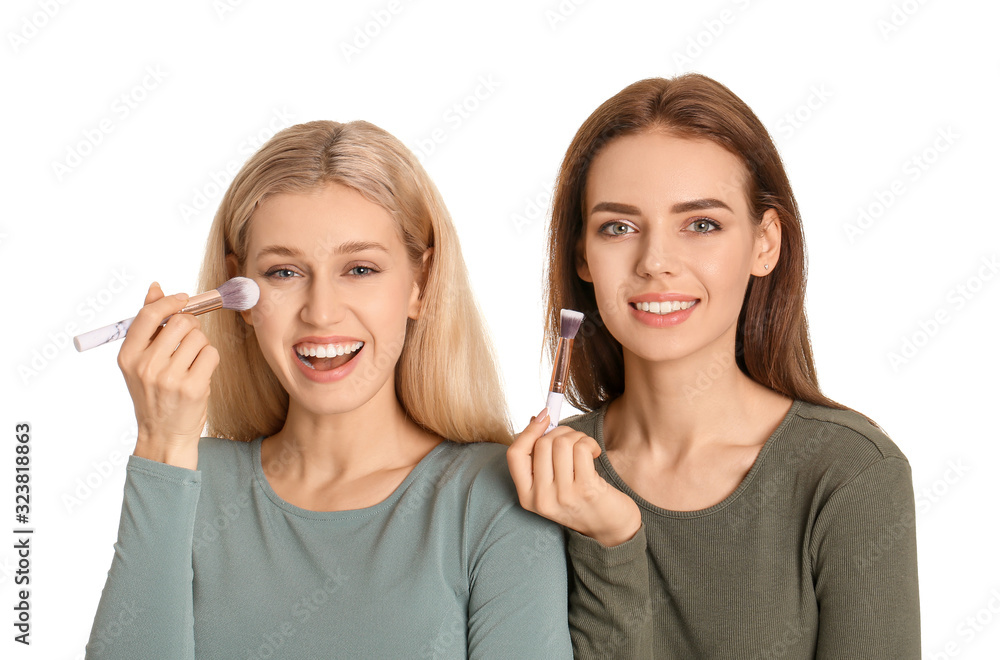 Beautiful young women applying makeup on white background