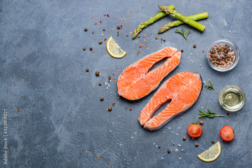 Raw salmon steaks and spices on dark background