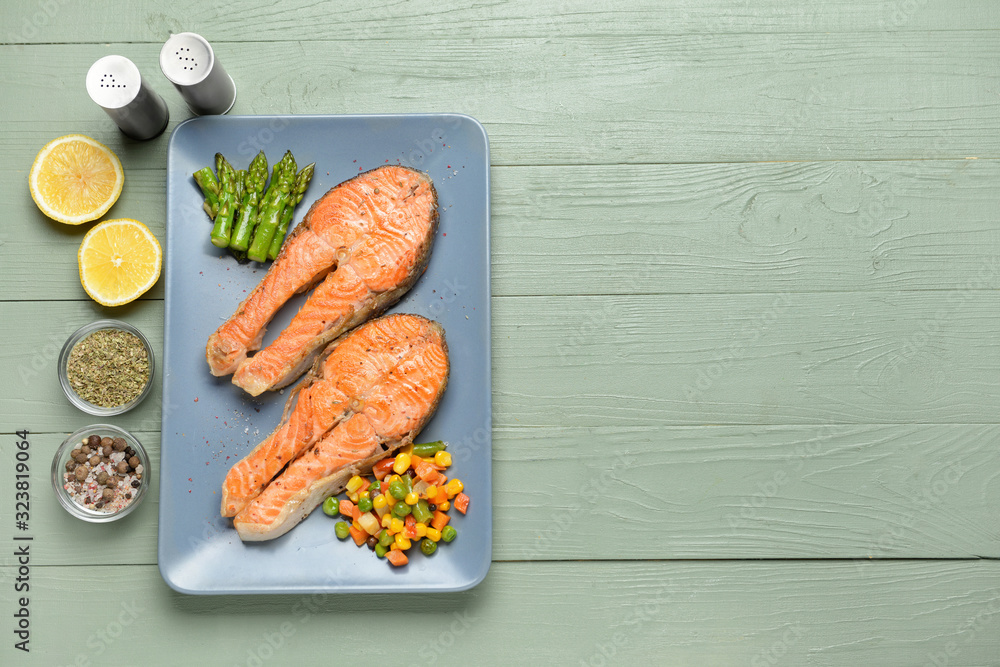 Plate with fried salmon and vegetables on table