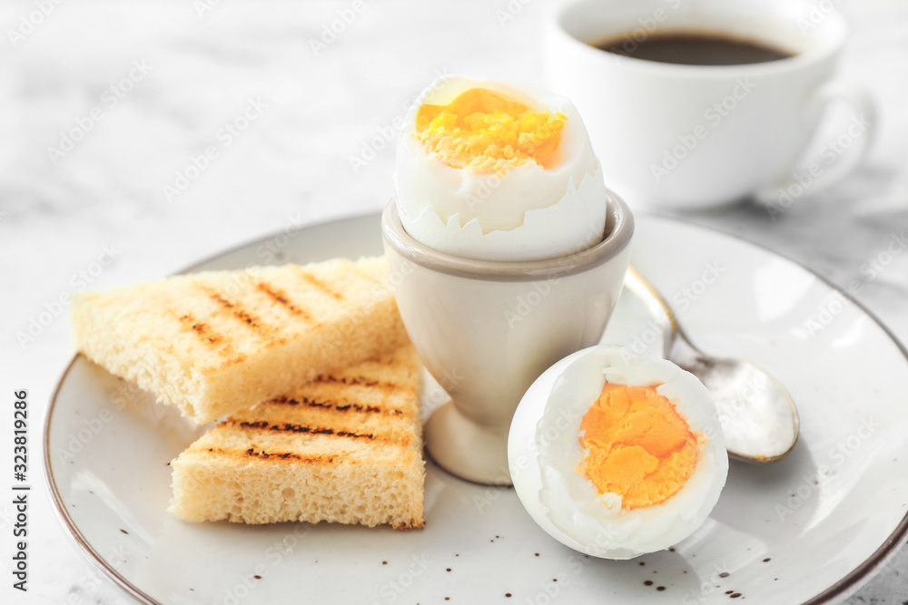 Plate with tasty boiled eggs and toasted bread on light background