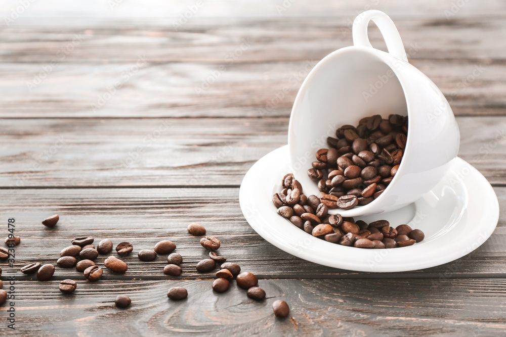 Cup with coffee beans on wooden background