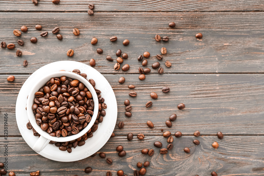 Cup with coffee beans on wooden background