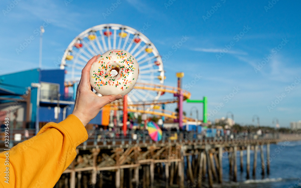 Female hand holding a donut on Santa Monica beach