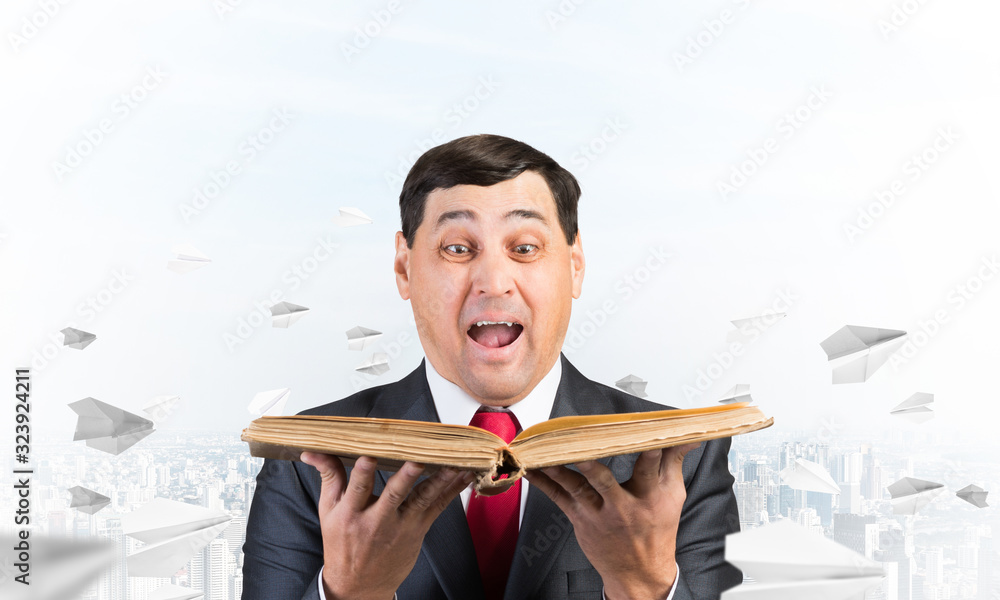 Surprised businessman holding open book