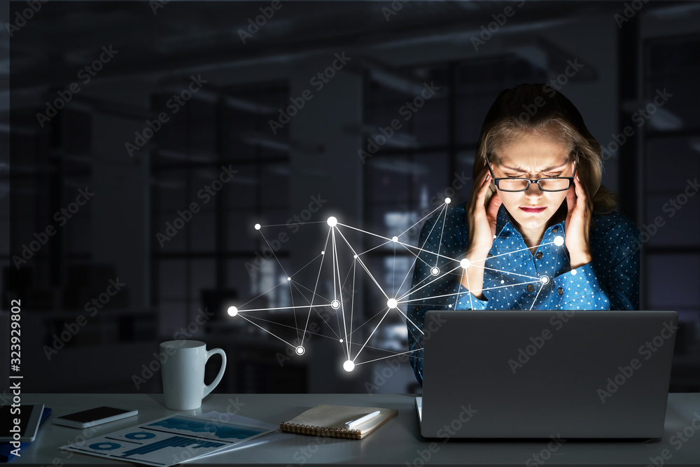 Attractive blonde wearing glasses in dark office using laptop. Mixed media