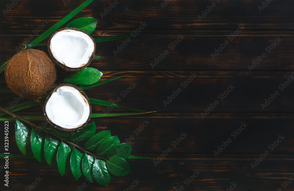 Coconut and moisturizer with green plants on an old wooden background with top view and copy space. 