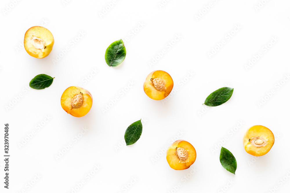 Peach slices and leaves background on white table top-down