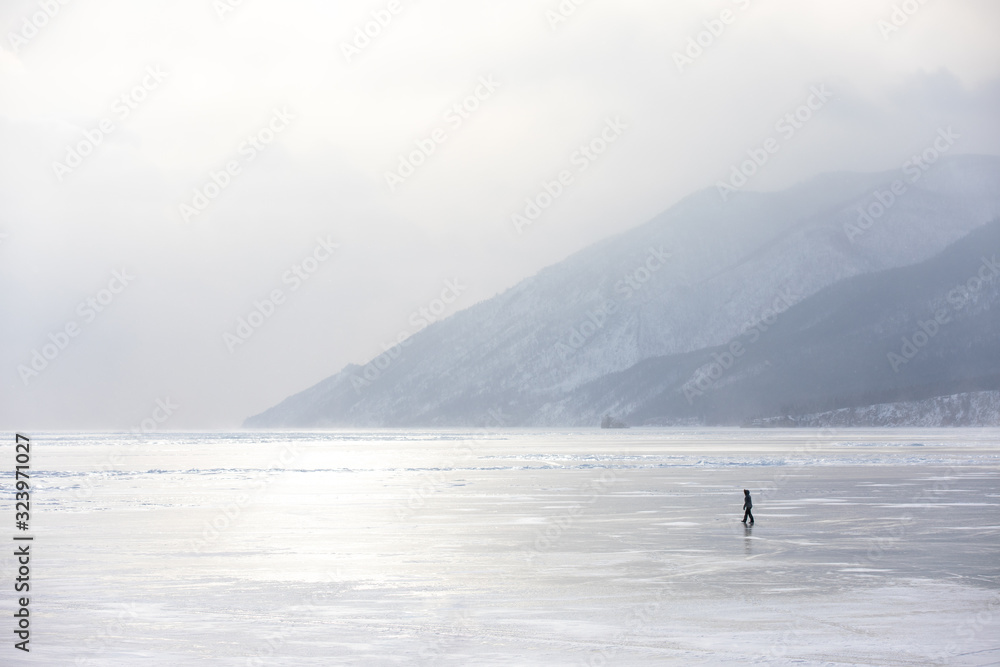 Woman walking on the frozen ice of lake Baikal on a windy day with a snow storm. Lake Baikal, Siberi