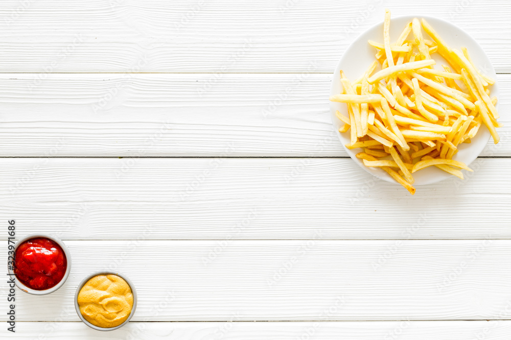 Fast food symbol. French fries on plate on white wooden table top-down copy space