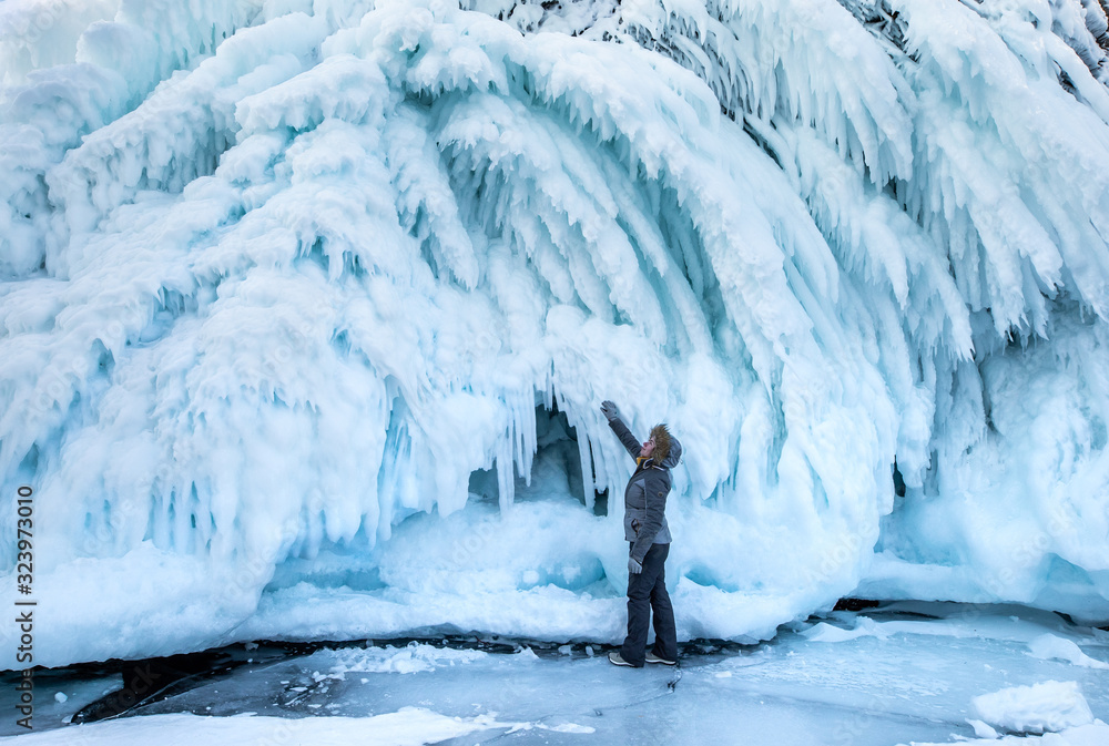 Woman marvelling at the massive wall of ice formed as a result of waves and wind. Lake Baikal, Siber