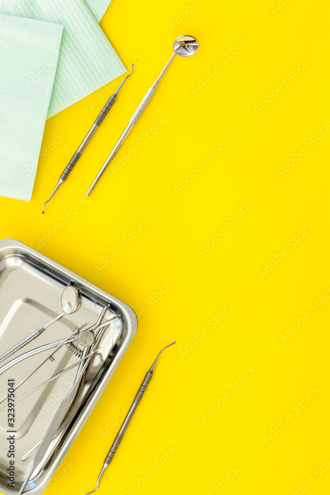 Dentak care concept. Stomatological tools in tray on yellow background top-down copy space