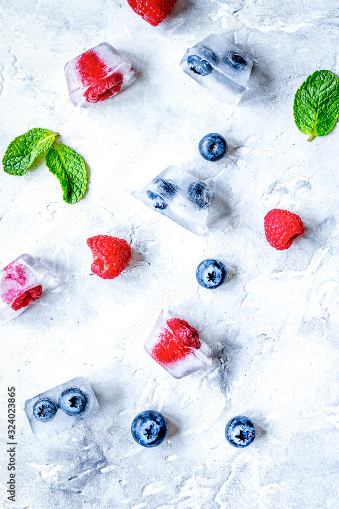 frozen berries in cubes on stone background top view