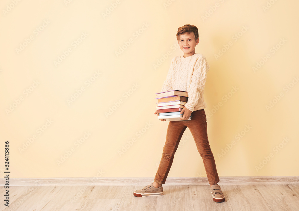 Little boy with books near color wall