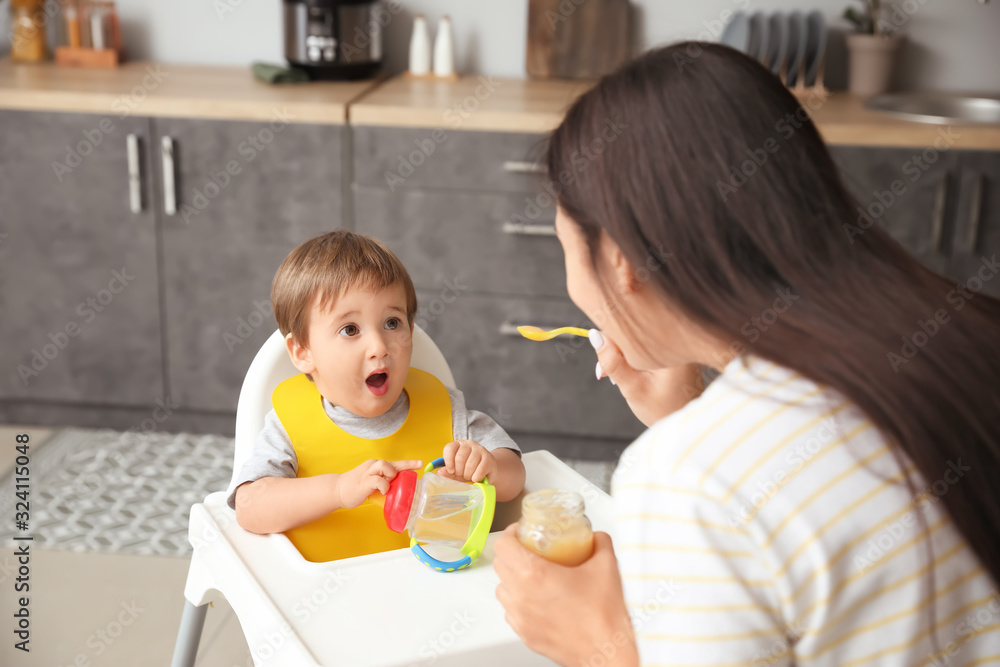 Mother feeding her little son in kitchen