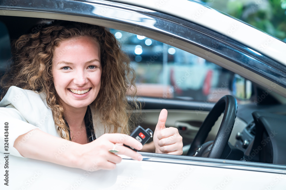 Caucasian female customer holding remote car key with smile and thumb up finger sitting in rental ca