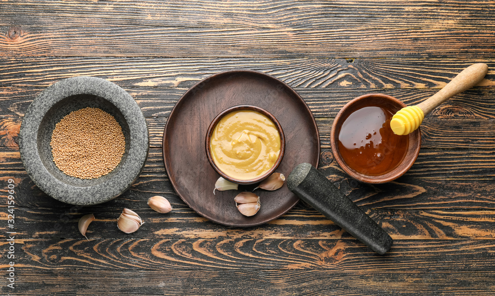 Bowl of tasty honey mustard sauce with ingredients on wooden background